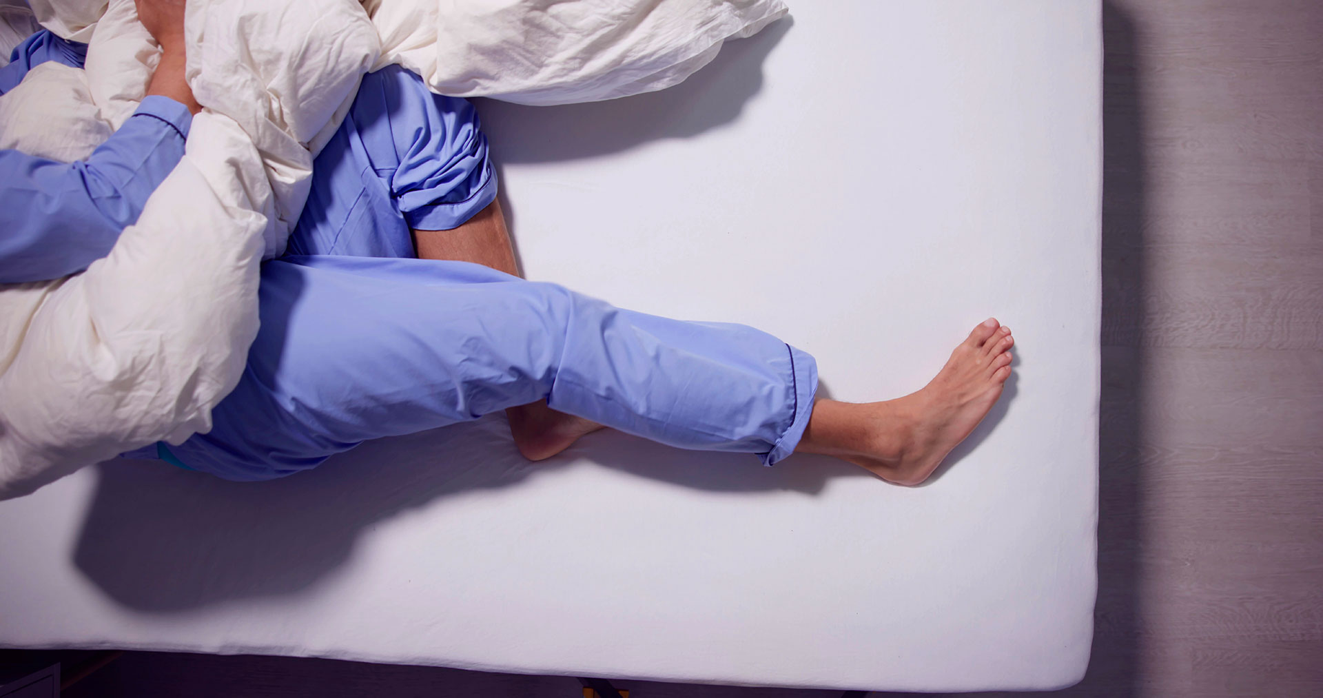 Person experiencing restless legs syndrome symptoms at night
