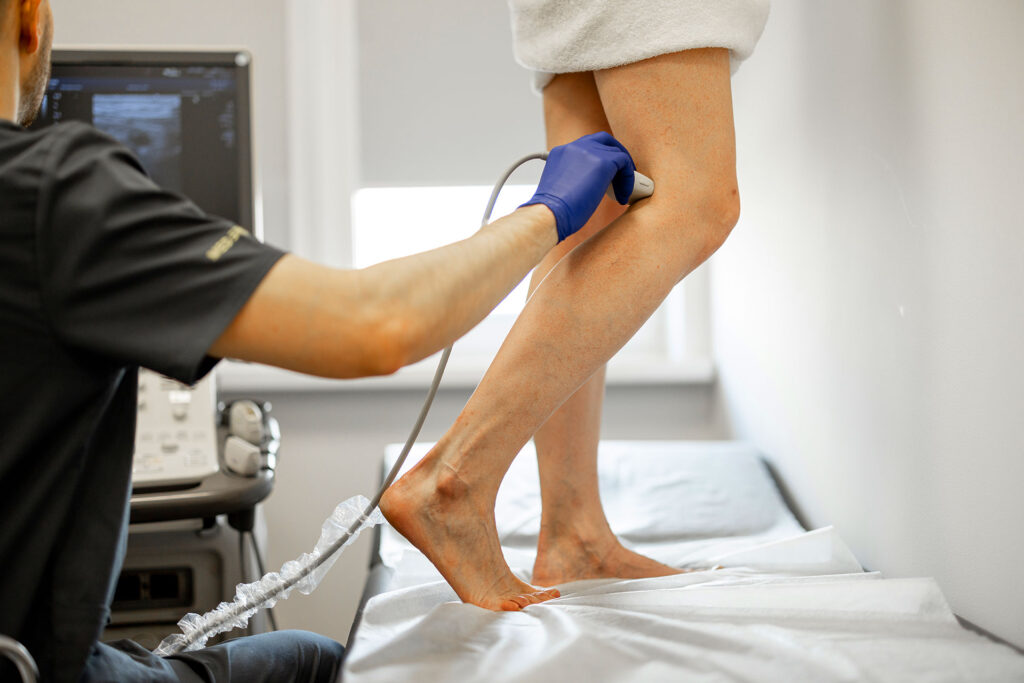  Phlebologist scanning standing patient's leg with ultrasound in modern vascular clinic