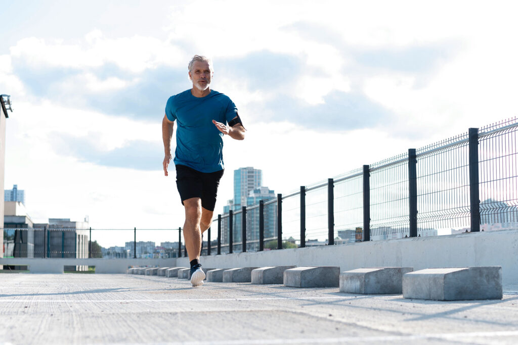 A man running on an elevated outdoor path near city buildings.