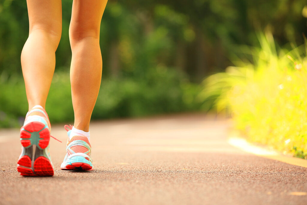 Back view of person walking in sneakers on outdoor path