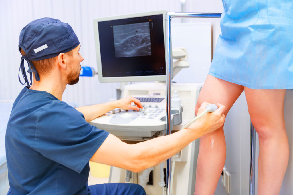 Sonographer conducting leg ultrasound exam in clinic