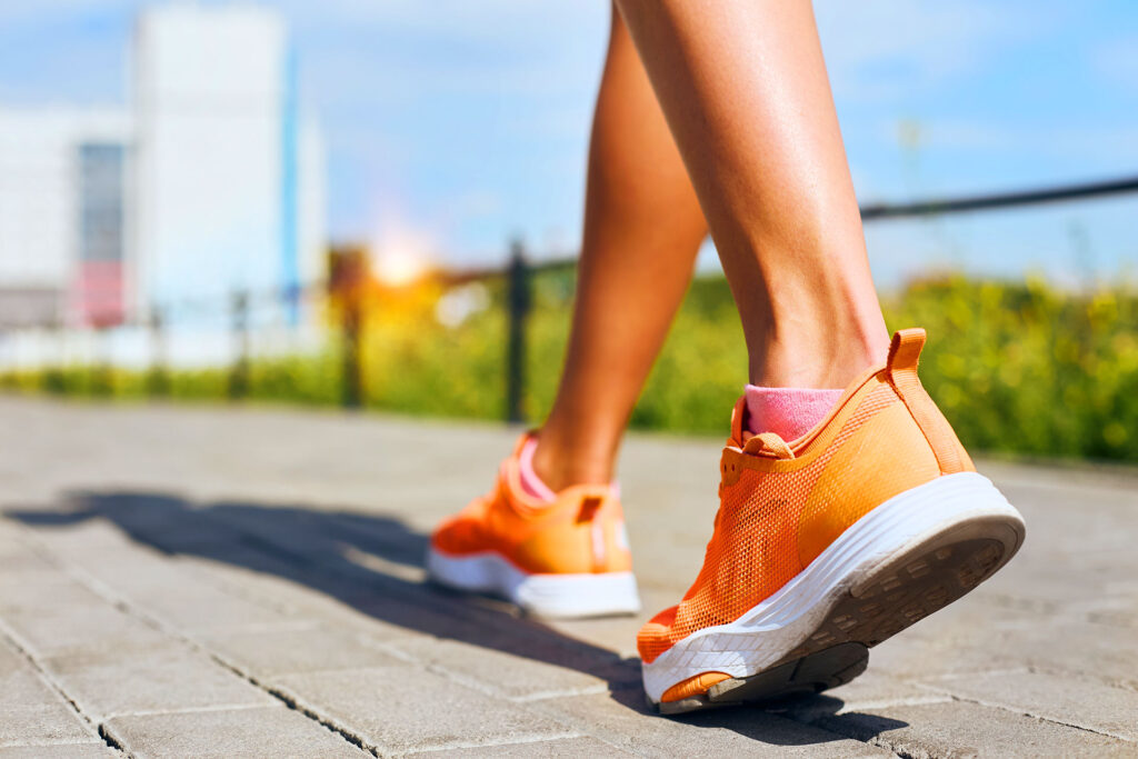 Close-up of woman walking in orange sneakers
