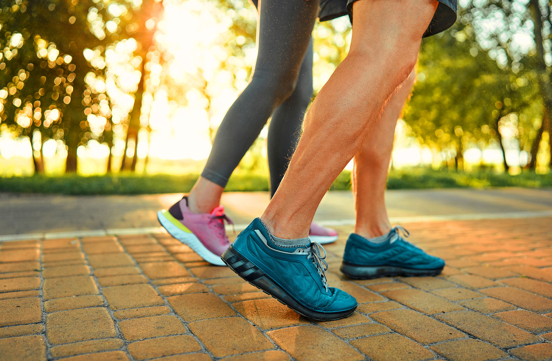 Two runners jogging on brick pathway outdoors