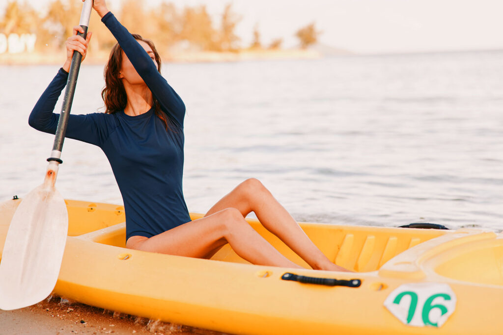 Woman paddling yellow kayak with legs stretched out front