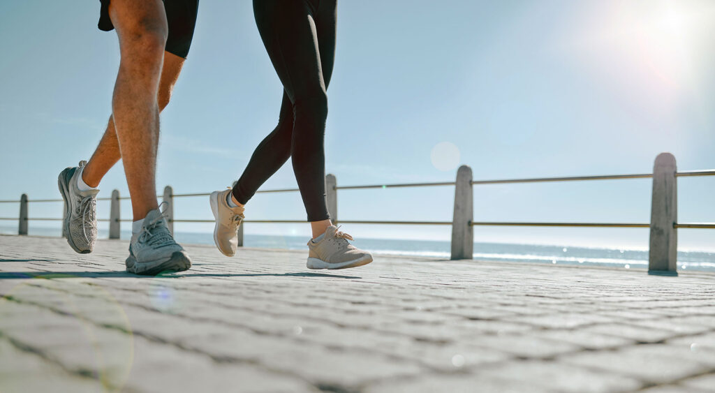 Couple walking briskly along boardwalk near ocean shoreline