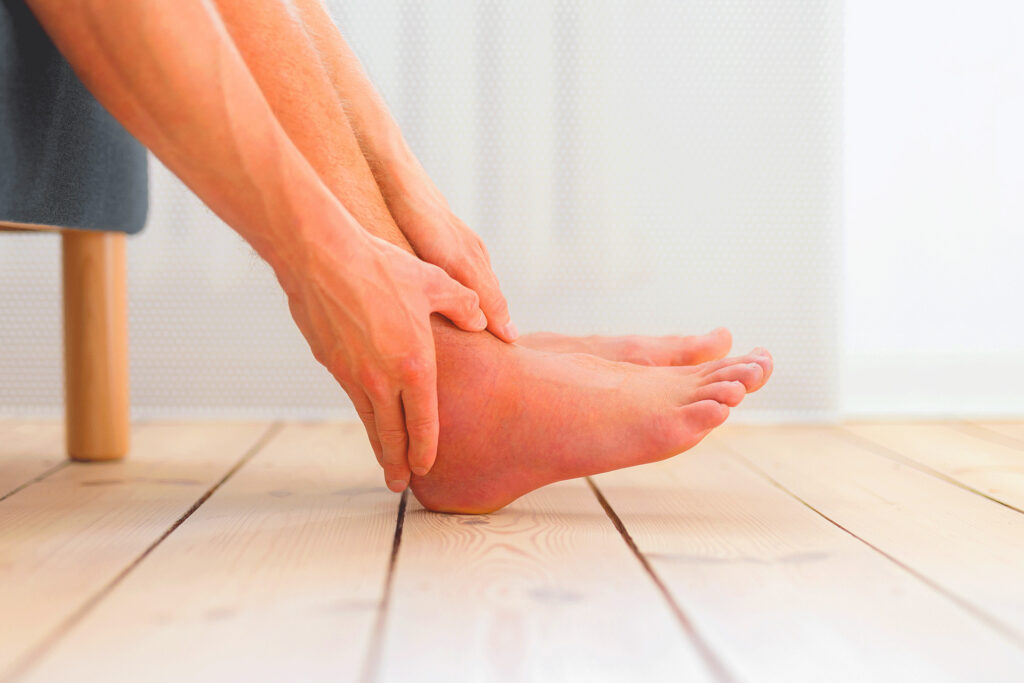 Close-up of a person holding their swollen ankle, relevant to discussions on vascular health and whether is blood blue.